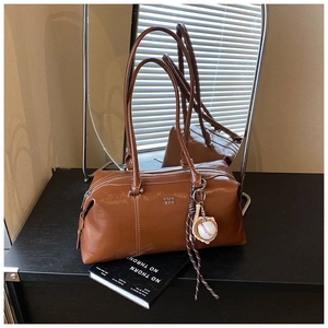 Detailed macro view of brown faux leather vintage Boston bag with a baseball glove keychain