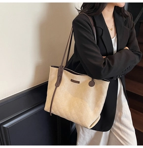 Detail of beige quilted suede tote bag with slim brown handles and metal fashion logo