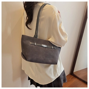 Side view of dark grey suede tote bag with decorative buckle on model's shoulder