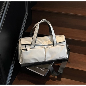 Détail du sac de voyage argenté avec poches multiples sur un escalier en bois