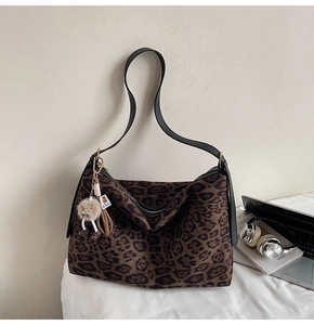 Détail du sac cabas en daim léopard avec bandoulière en cuir et breloque en peluche