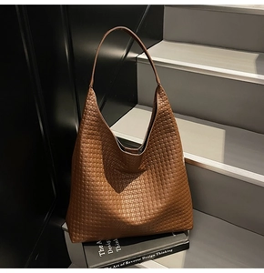 Detailed close-up of brown woven leather hobo tote bag placed on a staircase step
