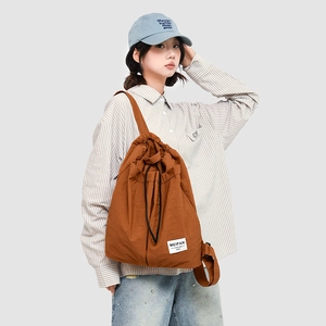 Close-up of brown nylon drawstring shoulder bag with Meifan label worn by a model