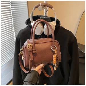Brown lychee grain Boston bag featuring a stylish beaded wooden charm and handle