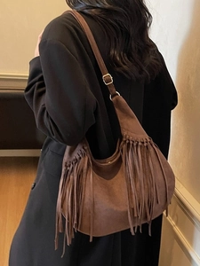 Brown suede hobo bag with long fringes and adjustable strap shown on model shoulder