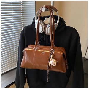 Macro view of vintage brown leather Boston bag with brand logo and baseball charm