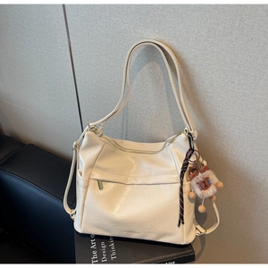 Detail of soft beige leather tote bag featuring a gold zipper and lion plush pendant
