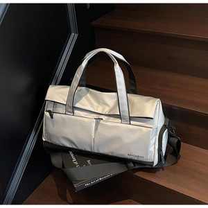 Détail du sac de sport gris argenté sur escalier montrant zips et tissu résistant à l'eau