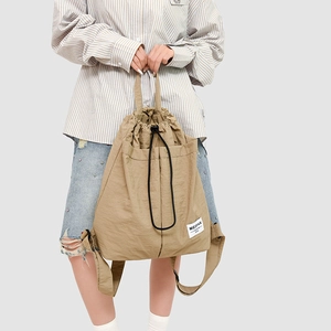 Detail of khaki drawstring backpack featuring meifan patch and large front pocket