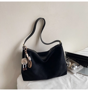 Détail du sac fourre-tout en daim noir avec fermeture éclair et porte-clé peluche mignon
