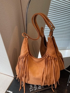 Vintage brown suede hobo bag with long fringes and metal buckle shown in a lifestyle setting