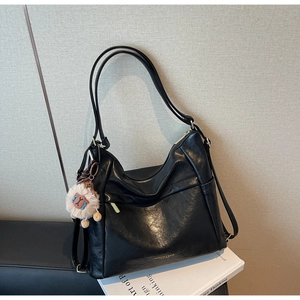 Detail of black hobo bag with gold hardware and a cute plush lion charm accessory