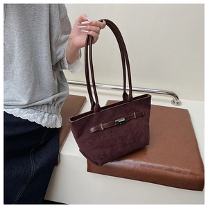 Detail of burgundy suede tote bag with slim leather straps and metal buckle closure