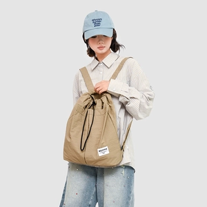 Close-up of khaki nylon drawstring backpack with signature woven label on minimalist design