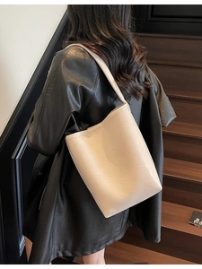 Minimalist beige PU leather tote bag with shoulder strap shown on model in stylish setting