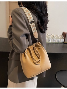 Sac seau beige chic avec large bandoulière jacquard porté par un mannequin en ville