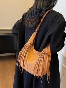 Vintage brown suede hobo bag with long fringes shown on model in a minimalist setting