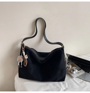 Détail d'un grand sac hobo noir en daim avec fermeture éclair et pendentif décoratif