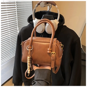 Detail of retro brown leather bowling bag with wooden bead charm and embossed logo