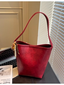 Minimalist red leather bucket bag with wooden bead charm for daily commuting style