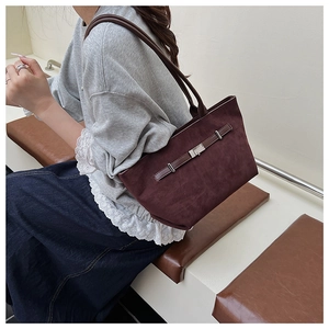 Detail of burgundy suede tote bag featuring a decorative leather strap and metal buckle