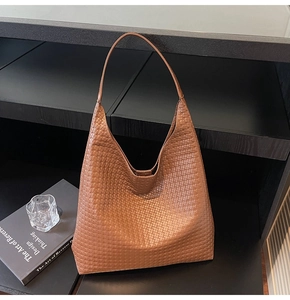 Detail of dark brown woven leather tote bag with Intrecciato texture and slim handles