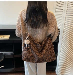 Détail du sac cabas léopard avec pendentif en peluche porté à l'épaule du mannequin