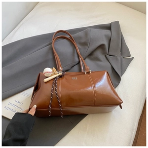 Detail view of brown glossy Boston bag with baseball charms and stripe rope deco