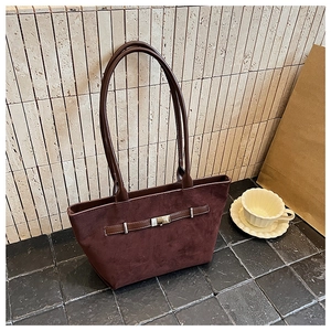 Close-up of deep brown suede tote bag with leather strap and metal buckle detail