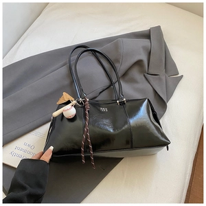 Detail of glossy black Boston bag with creative baseball pendant and metal logo detail