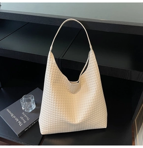Detailed close-up of the woven texture and cream-white leather finish on this tote bag