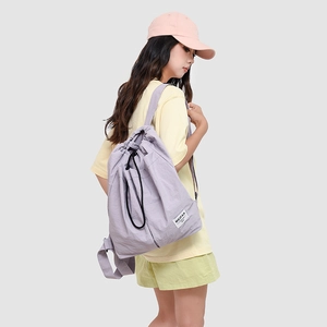 Detail view of a light purple drawstring backpack with black cords and side pockets