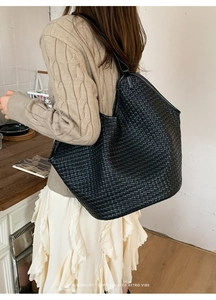 Close-up of a black woven leather hobo tote bag featuring a minimalist retro weave pattern