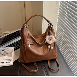 Detail of dark brown faux leather hobo bag with alpaca charm on a leather mat
