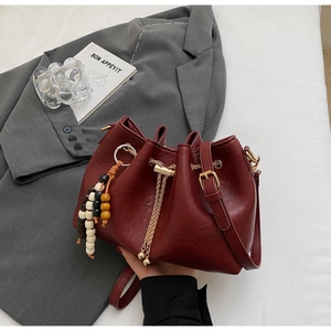Detailed shot of dark red leather bucket bag with gold hardware and beaded tassel charm