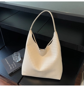 Detail of cream woven leather texture and soft handle on minimalist hobo shoulder bag