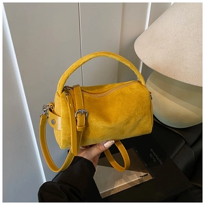 Detail der gelben Wildleder-Zylindertasche mit silberner Metallschnalle und Schultergurt