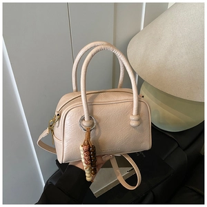 Close-up of beige bowling bag with textured PU leather, beads, and matte gold hardware