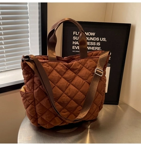 Detail of dark brown quilted nylon tote bag featuring diamond pattern and wide strap