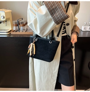 Detail of black matte suede mini tote bag with decorative colorful wooden bead tassels