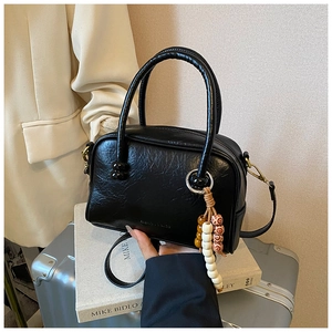 Detail of black glossy leather Boston bag with wooden beads and round metal handles