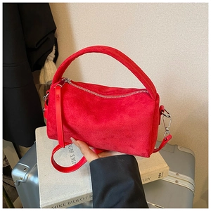 Detail der roten Wildleder-Tasche mit Metallreißverschluss auf Vintage-Büchern