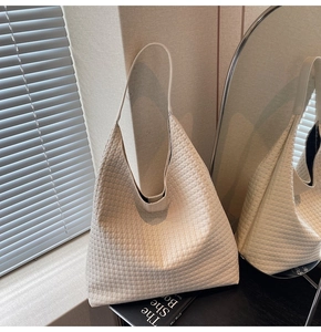 Close-up of woven texture and hobo shape on a cream-colored minimalist shoulder bag