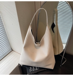 Detailed view of woven beige tote bag with hobo style texture and slim shoulder straps
