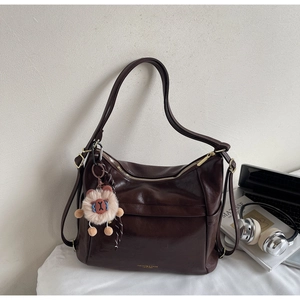 Detail of dark brown matte faux leather tote bag with stylish plush lion keychain charm
