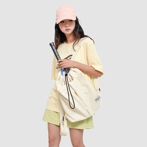 Detail of a beige canvas drawstring backpack with functional pockets and branding label