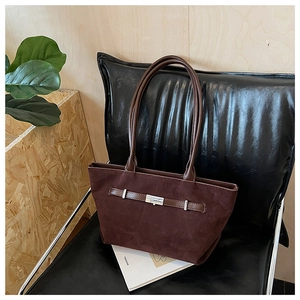 Detail of dark brown suede tote bag with leather strap and silver metal buckle accent