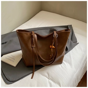Dettaglio borsa tote in pelle marrone vintage con nappa in legno su tessuto di lino
