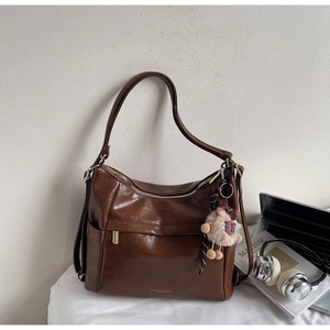 Detailed close-up of a brown PU leather tote bag with gold hardware and plush charm