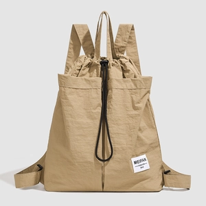 Close-up of khaki nylon drawstring backpack with signature woven label and fabric texture